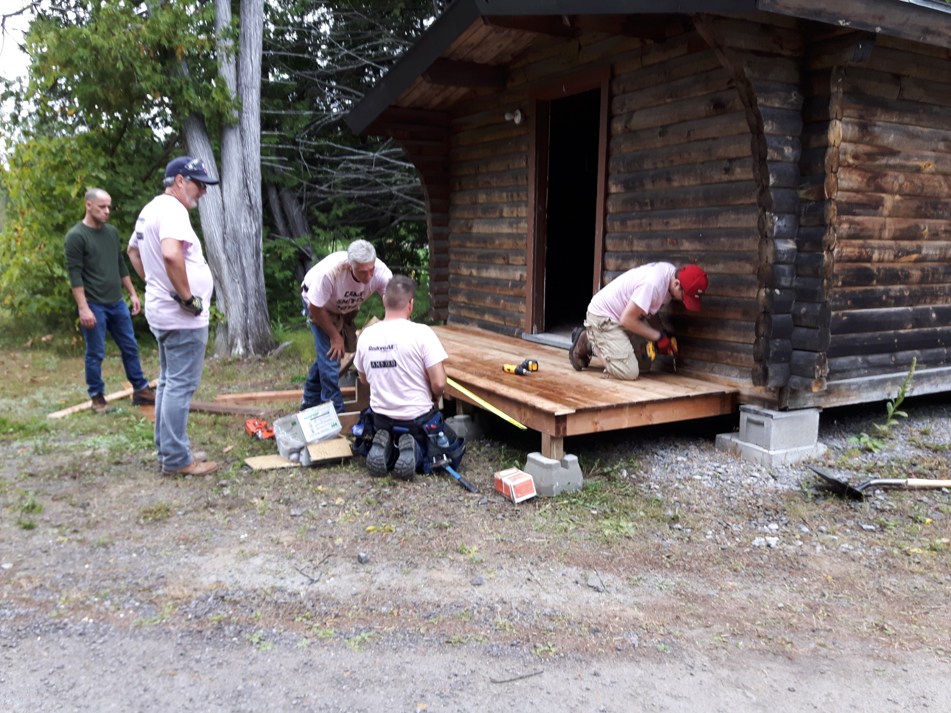 Photo of five people working on building a cabin