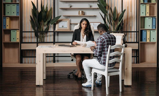 A woman meets with a client at her desk.