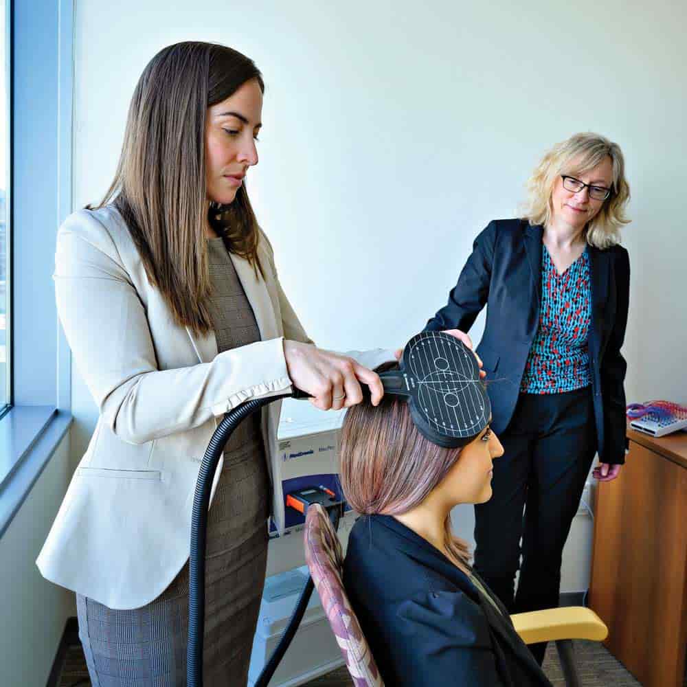 A woman holds a medical device to a patient's head